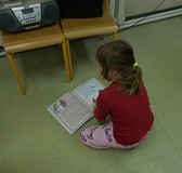 Dziewczynka odwrócona tyłem ogląda bajkę o Calineczce