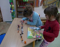 Dwoje dzieci przy stoliku lepią z plasteliny Muminki