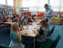 Dzieci przy stolikach wykonują prace plastyczne