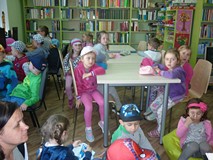 Dzieci siedzą w czytelni i słuchają opowiadania o Muminkach