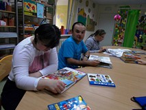 Kilka osób przy stolikach z książkami