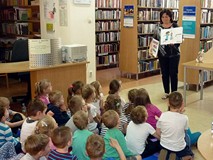 Bibliotekarka pokazuje dzieciom plansze, które zostały wykonane na naszych zajęciach bibliotecznych