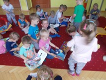Dzieci siedzą na dywanie i oglądają książki