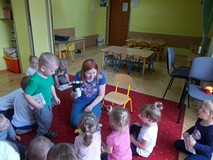 Dzieci stoją wokól bibliotekarki, która trzyma pacynkę w ręku