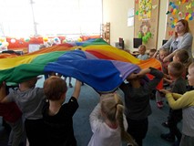 Dzieci wraz z bibliotekarką podnoszą do góry chustę animacyjną