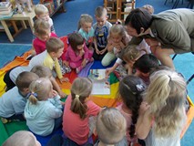 Dzieci wraz z leśniczyną ogląda ilustracje w książce