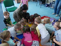 Leśniczyna wraz z dziećmi pochyla się nad książką