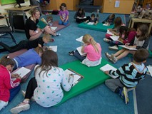 Dzieci siedzą na dywanie rysując ilustracje do czytanego tekstu