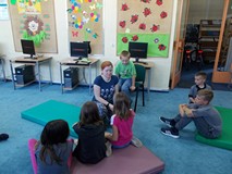 Bibliotekarka przeprowadza zabawę mówiąc coś do dziewczynki