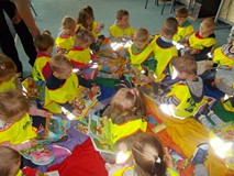 Dzieci siedzą na chuście i oglądaja książeczki