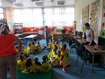 Dzieci siedzą na materacach, a bibliotekarka pokazuje im pacynkę