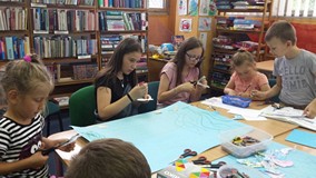 Dzieci siedzą przy stole i wykonują plakat