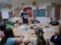 Dzieci zgromadzone przy stole poznają zasady segregacji odpadów