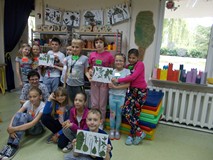 Grupa dzieci z panią bibliotekarką z dumą pokazują zielniki