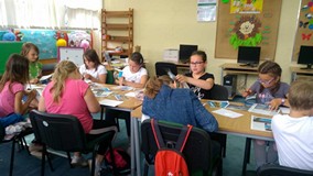 Dzieci siedzą przy stole i wykonują kartki pocztowe