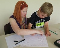 Bibliotekarka pomaga chłopcu w rysowaniu okładki do komiksu