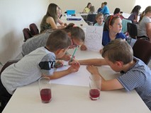 Dzieci siedzą przy stoliku i w grupie rysują komiks