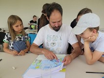 Pan Artur pokazuje coś na rysunku dziewczynce i chłopcu