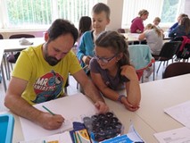 Pan Artur rysuje komiks a dziewczynka i chłopiec przyglądają się temu