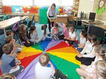 Bibliotekarka pokazuje dzieciom siedzącym na chuście książki o Neli, małej podróżnicce