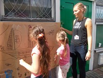 Bibliotekarka wspiera pracę dzieci podczas malowania farbami