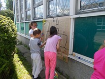 Grupa dzieci wspólnie maluje farbami