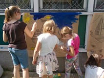 Trzy dziewczynki malują farbami statek