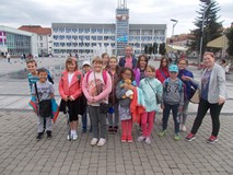 Dzieci z bibliotekarką pozują do zdjęcia przed ratuszem