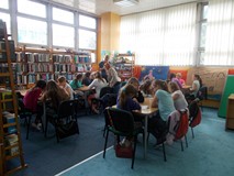 dzieci siedzą przy stołach rozwiązując zagadki