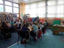 Dzieci siedzą przy stołach i bawią się w zabawy słowne