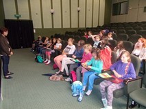 dzieci siedzą na widowni i słuchają opowieści pisarki