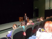 dzieci siedzą na widowni i słuchają opowieści pisarki