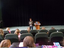 dzieci siedzą na widowni i słuchają opowieści pisarki