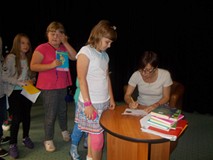 Pisarka podpisuje dzieciom książki