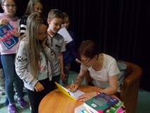 Pisarka podpisuje dzieciom książki