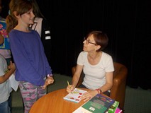 Pisarka podpisuje dzieciom książki