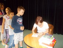 Pisarka podpisuje dzieciom książki