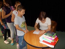 Pisarka podpisuje dzieciom książki