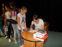 Pisarka podpisuje dzieciom książki