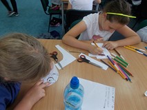 Dwie dziewczynki siedzą przy stole i kolorują pirata