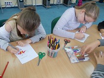 Dzieci siedzą przy stole i kolorują pirarta