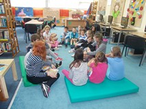 Dzieci siedzą w kole, a bibliotekarka opowiada ciekawostki marynistyczne