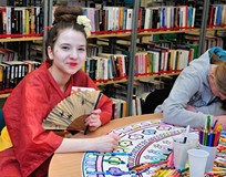 W czasie Orientalnej Nocy w Bibliotece przy stole w czytelni pozuje dziewczyna przebrana za gejszę z