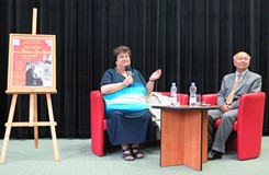 Na scenie w sali konferencyjno-kinowej Koszalińskiej Biblioteki Publicznej siedzi tłumacz literatury