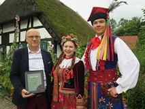 W czasie Narodowego Czytania 2017 w Koszalinie młoda para w strojach ludowych pozuje wraz z dyrektor