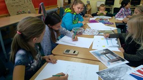 Dzieci siedzą przy stole i wykonują prace plastyczne o londyńskich zabytkach