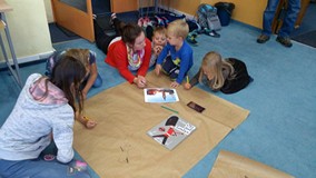 Dzieci wraz z rodzicami zapisują na plakacie ciekawostki o Londynie