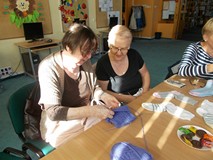 Dwie Panie siedzą przy stole, rozmawiając o technice robienia na drutach