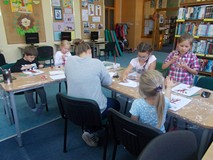 Dzieci siedzą przy stole i wykonują prace plastyczne