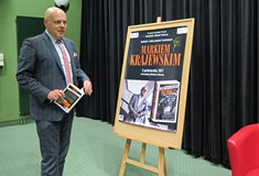 Marek Krajewski przed plakatem promującym jego spotkanie